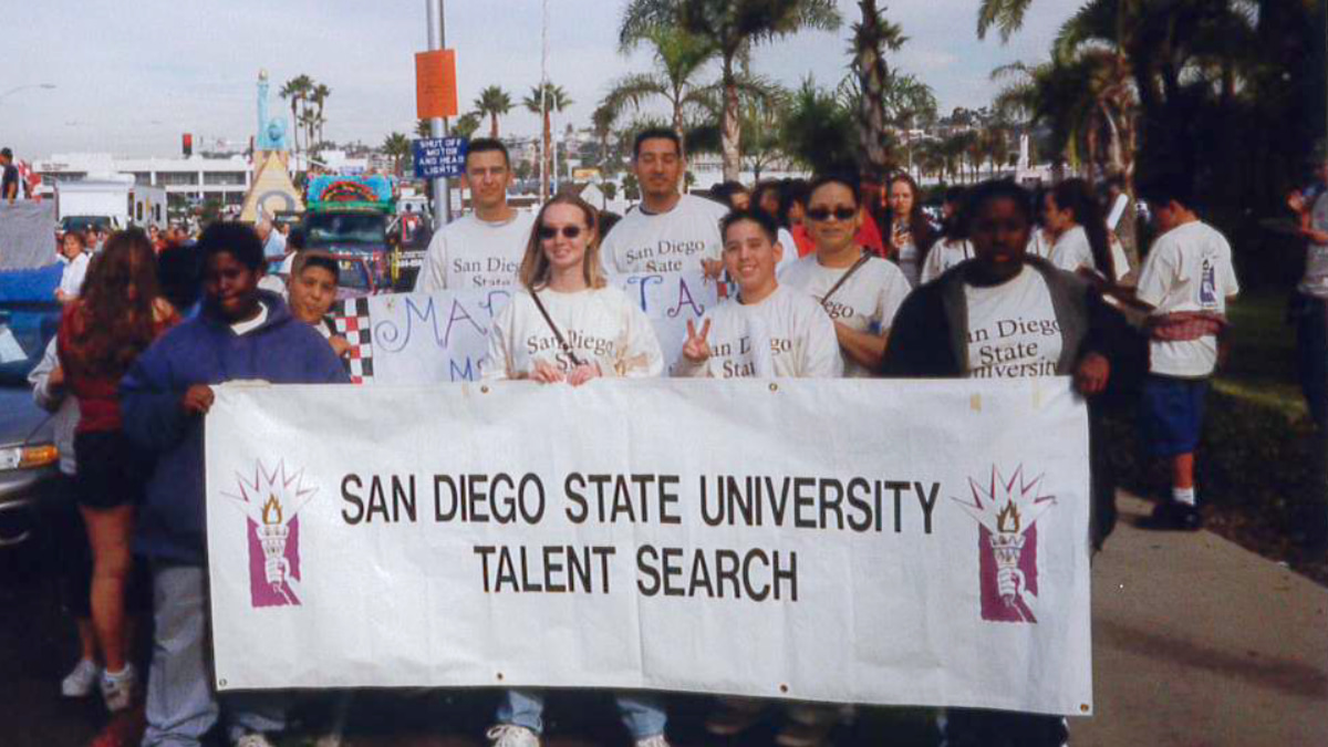 A group of students pose for a group photo while holding a large sign with the words "Talent Search Program" on them