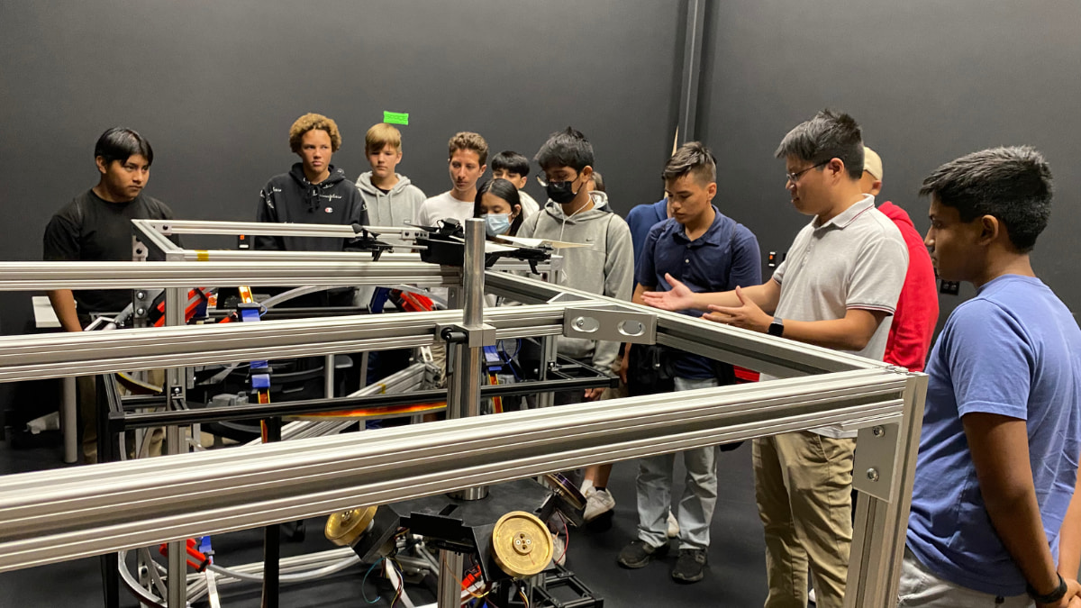 A group of students take a closer look at a large and complex machine in front of them